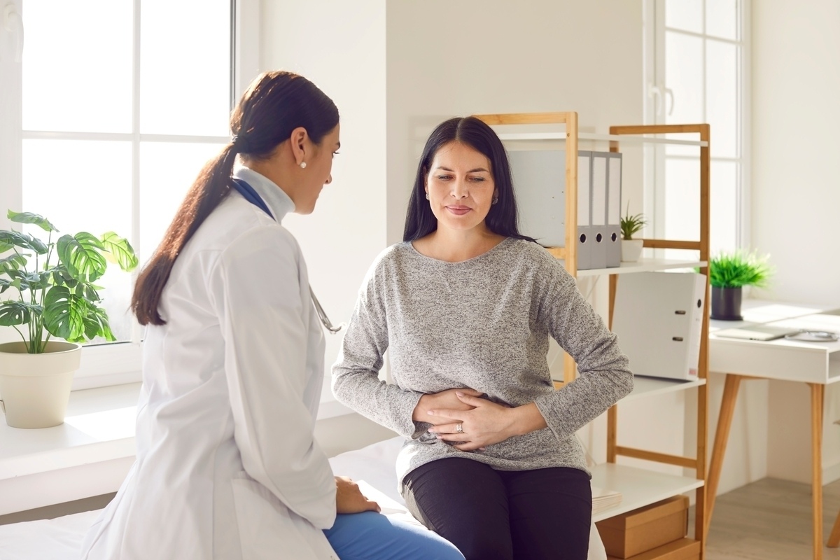 Woman holding her stomach during a clinical consultation with her provider to discuss GLP-1 medication side effects and digestive discomfort