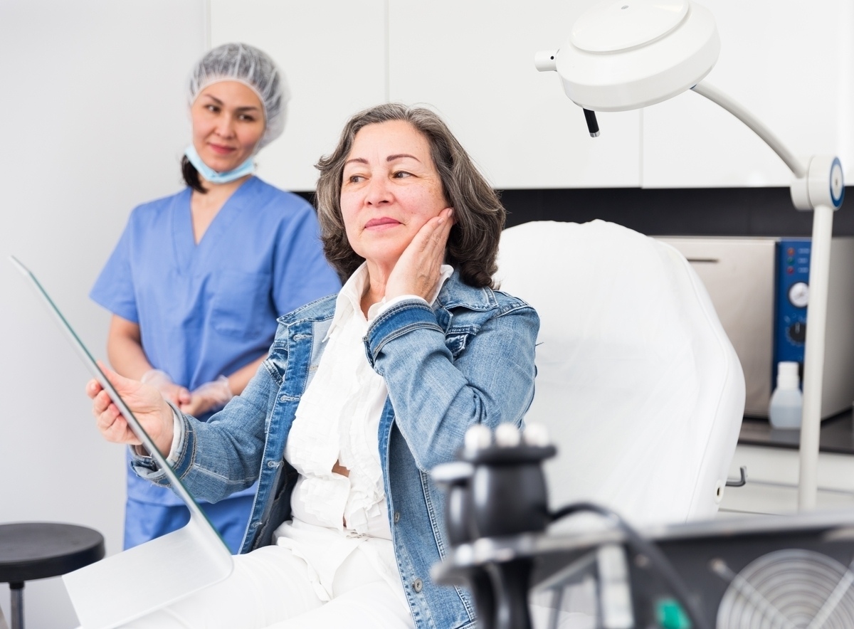 Mature woman touching her cheek during a consultation to discuss whether dermal fillers dissolved is the right option for her results
