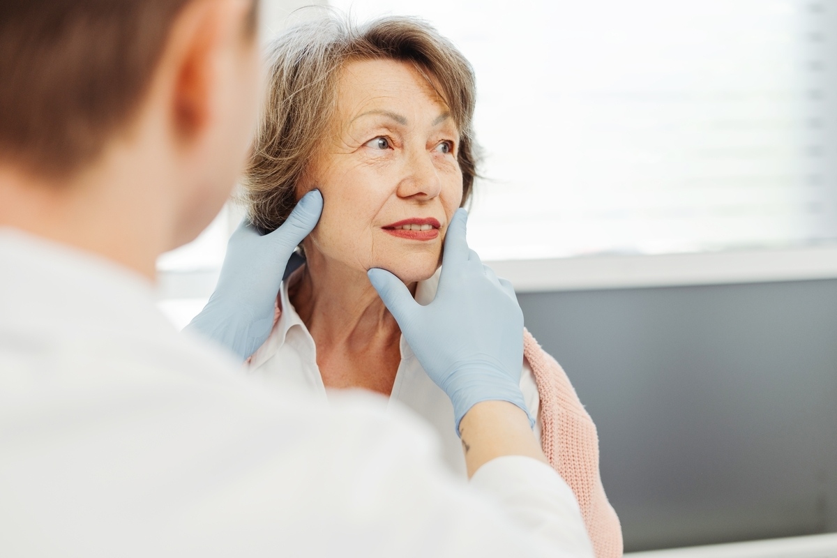 Provider assessing a mature woman's face during a consultation to discuss the types of wrinkle relaxers including Botox Dysport and Daxxify